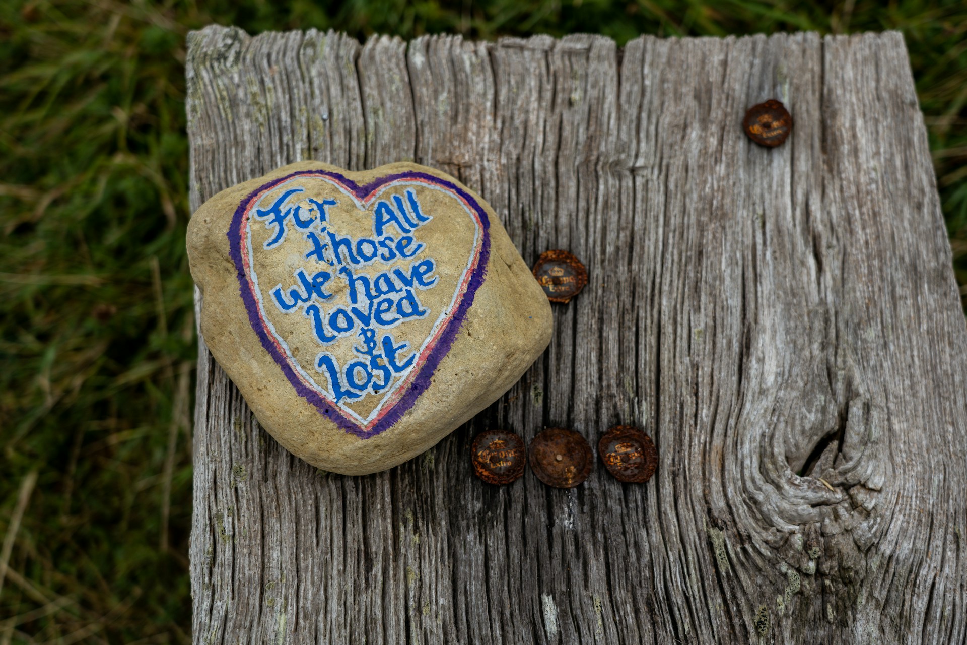 A hand-painted stone reading 'For all those we have loved and lost'